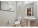 Half bathroom with a pedestal sink, toilet, and modern artwork at 2648 Florence St, Denver, CO 80238