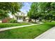 Well-manicured lawn with lush trees surrounding a charming home with a welcoming front porch at 2648 Florence St, Denver, CO 80238