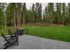 Deck with wooden chairs and a grill, set against a backdrop of towering trees at 563 Cr 672, Breckenridge, CO 80424