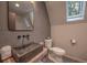 Bathroom with gray tiled walls, modern sink, and toilet next to a large mirror and window at 563 Cr 672, Breckenridge, CO 80424