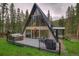A-frame home featuring a modern design, large windows, a deck with a hot tub and grill, surrounded by lush trees at 563 Cr 672, Breckenridge, CO 80424