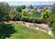 Landscaped backyard with a lush lawn, mature trees, garden beds, and a view of neighborhood homes at 11715 Crow Hill Dr, Parker, CO 80134