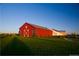 Striking red barn with white accents stands out against a lush green field and clear blue sky at 10912 Memphis Ct, Commerce City, CO 80022