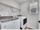 Bright laundry room features modern washer and dryer units with overhead shelving at 10912 Memphis Ct, Commerce City, CO 80022