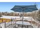 Outdoor deck with table, umbrella, and seating overlooking a snow covered common area at 6366 Nassau Ct, Highlands Ranch, CO 80130