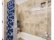 Tiled bathroom with a bathtub and blue patterned shower curtain; storage in the corner at 6366 Nassau Ct, Highlands Ranch, CO 80130