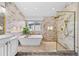Stunning bathroom featuring marble tile, soaking tub, frameless shower with gold accents, and modern fixtures at 6427 S Tibet St, Aurora, CO 80016