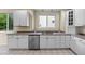 Bright kitchen with white cabinets, neutral countertops, stainless steel dishwasher, and natural light at 6427 S Tibet St, Aurora, CO 80016
