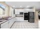 Open kitchen with stainless steel appliances, white cabinetry, tile floors, and an adjacent dining area at 6427 S Tibet St, Aurora, CO 80016