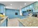 Well-appointed kitchen featuring blue cabinets, granite countertops, stainless steel appliances, and tile flooring at 1552 W Caley Ave, Littleton, CO 80120