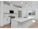 Bright open kitchen features white cabinets, stainless steel appliances, a large island with white countertops and hardwood floors at 3109 Bates Ave, Denver, CO 80236