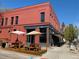Red brick building with an outdoor seating area, featuring picnic tables under patio umbrellas at 3337 Decatur St, Denver, CO 80211