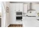 Close-up of kitchen featuring white cabinets, subway tile backsplash, stainless steel appliances, and wood flooring at 7678 S Old Hammer Way, Aurora, CO 80016
