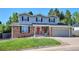 Charming two-story home featuring brick and gray siding, manicured lawn, and a vibrant red front door at 7822 W Ottawa Pl, Littleton, CO 80128