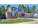 Charming two-story brick home with a covered front porch, a vibrant red door, and a manicured front lawn at 7822 W Ottawa Pl, Littleton, CO 80128