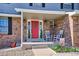 Inviting covered front porch with rocking chairs and red door featuring a wreath and stylish decorations at 7822 W Ottawa Pl, Littleton, CO 80128