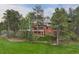 Back exterior of a multi-level brick home surrounded by lush greenery and trees, set on a golf course at 120 Silver Leaf Way, Castle Rock, CO 80108