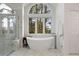 Bright bathroom with marble tile, walk-in shower and soaking tub below large window at 120 Silver Leaf Way, Castle Rock, CO 80108