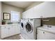 Bright laundry room with white cabinetry, ample counter space, modern washer and dryer, and utility sink at 120 Silver Leaf Way, Castle Rock, CO 80108