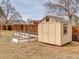 Tan backyard shed with wood trim and a small window is situated next to a fenced garden at 6523 S Field Way, Littleton, CO 80123