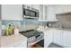 Close-up of the modern stainless steel stove, microwave, and quartz countertops in the updated kitchen at 6523 S Field Way, Littleton, CO 80123