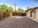 Gravel backyard features a stone accent and leads to a wooden fence with trash receptacles at 5995 Estes St, Arvada, CO 80004
