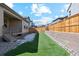 Backyard with green synthetic grass, wood fence, and stone retaining wall, creating a private outdoor space at 17163 Desert Wine Trl, Parker, CO 80134