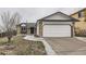 Charming home featuring stone accents, white siding, and a two-car garage, all under an overcast sky at 6102 S Owens Ct, Littleton, CO 80127