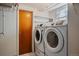Laundry room with white washer and dryer units, tile floor, and a wooden door at 3540 Vrain St, Denver, CO 80212