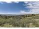 Scenic aerial view of rolling hills, lush trees, and mountain vistas under a vibrant blue sky at 1562 Suncrest Rd, Castle Rock, CO 80104