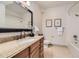 Bathroom with granite-topped vanity and framed mirror, complemented by neutral tile flooring and shower at 1562 Suncrest Rd, Castle Rock, CO 80104
