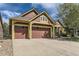 A view of the home highlighting the three car garage and brown and tan color scheme at 1562 Suncrest Rd, Castle Rock, CO 80104