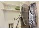 Modern laundry room featuring a stacked washer and dryer set with open shelving for ample storage at 1562 Suncrest Rd, Castle Rock, CO 80104