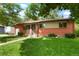 Inviting single-story brick home with lush lawn and garden, complemented by a quaint front porch and attached garage at 6371 Brooks Dr, Arvada, CO 80004