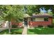 Charming brick home featuring a well-manicured lawn, a flower-adorned entrance, and a welcoming wreath on the door at 6371 Brooks Dr, Arvada, CO 80004