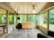 Bright sunroom with ceiling fan and vinyl flooring surrounded by lush greenery visible through the many windows at 6371 Brooks Dr, Arvada, CO 80004