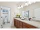 Bathroom with double sinks, granite countertops, dark wood cabinets, and tile flooring at 15987 E 115Th Pl, Commerce City, CO 80022