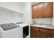 Functional laundry room with modern washer and dryer, granite countertop, and ample storage at 15987 E 115Th Pl, Commerce City, CO 80022