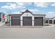 A row of three private garages with gray doors and white siding stands under a blue sky at 3550 W 63Rd Ave, Denver, CO 80221