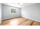 Bright bedroom featuring hardwood floors, modern lighting, and a large window with tree views at 2484 E 101St Ct, Thornton, CO 80229