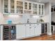 Stylish wet bar featuring white cabinets, glass shelving, mosaic backsplash, and dual wine refrigerators at 6269 S Coventry E Ln, Littleton, CO 80123