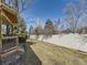 View of fenced backyard with mature trees, grass, and access to a second story deck at 6194 E Briarwood Cir, Centennial, CO 80112