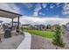Landscaped backyard with a large lawn, trees, and a covered patio at 5392 Sanctuary Ave, Firestone, CO 80504