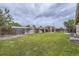Spacious backyard featuring lush grass, a wood fence, a covered patio, and mature trees at 664 Stampede Dr, Brighton, CO 80603