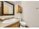 Cozy bathroom featuring a decorative mirror, wood storage cabinet, toilet, and a vanity with a white sink at 664 Stampede Dr, Brighton, CO 80603