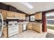 Functional kitchen with light wood cabinets, white appliances, and convenient access to the outdoors at 664 Stampede Dr, Brighton, CO 80603