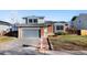 Inviting two-story home with a gray garage door, brick details, and a lovely walkway to the entrance at 19697 E Flora Pl, Aurora, CO 80013