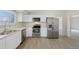Well-lit kitchen featuring white cabinets, stainless steel appliances, and wood grain flooring at 19697 E Flora Pl, Aurora, CO 80013