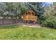 Backyard playhouse offers a charming space for children, surrounded by green grass and mature trees at 2555 S Zang St, Denver, CO 80228