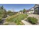Lush backyard featuring a manicured lawn, mature trees, and garden beds at 21701 E 50Th Dr, Aurora, CO 80019